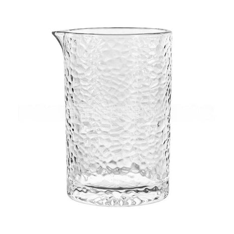 A clear glass mixing glass with a geometric pattern and a brown liquid inside, alongside an empty glass with a geometric pattern | Cocktail Ceremony