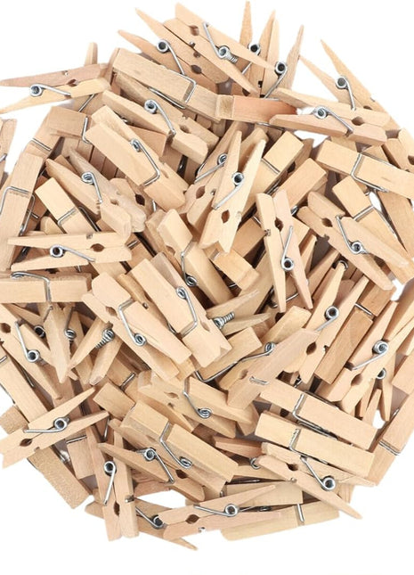 Collection of wooden clothespins with a hand holding one, on a white background.