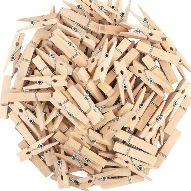 Collection of wooden clothespins with a hand holding one, on a white background.