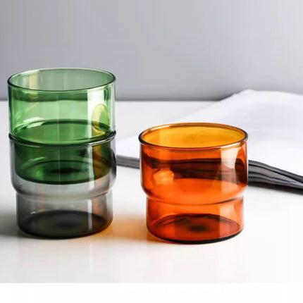 Stack of colorful glass cups on a white surface with a gray background