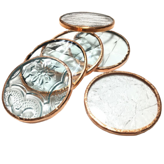 Set of four round glass coasters with copper rims on a white background