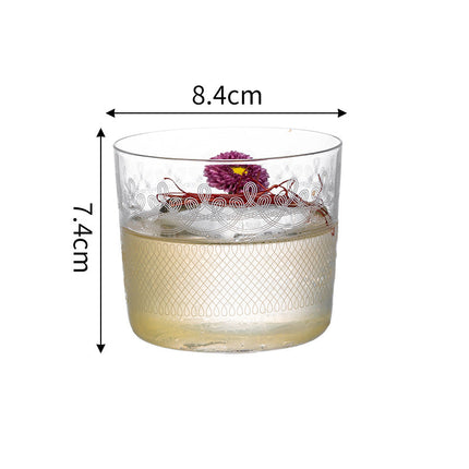 Glass tumbler with floral design and measurements on a white background