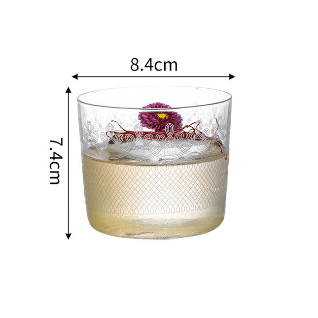Glass tumbler with floral design and measurements on a white background